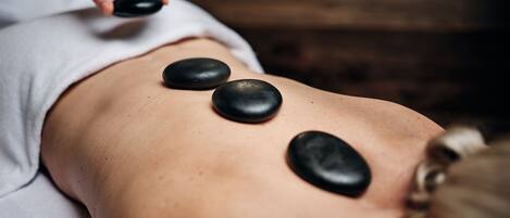 A person receiving a back massage with stones.
