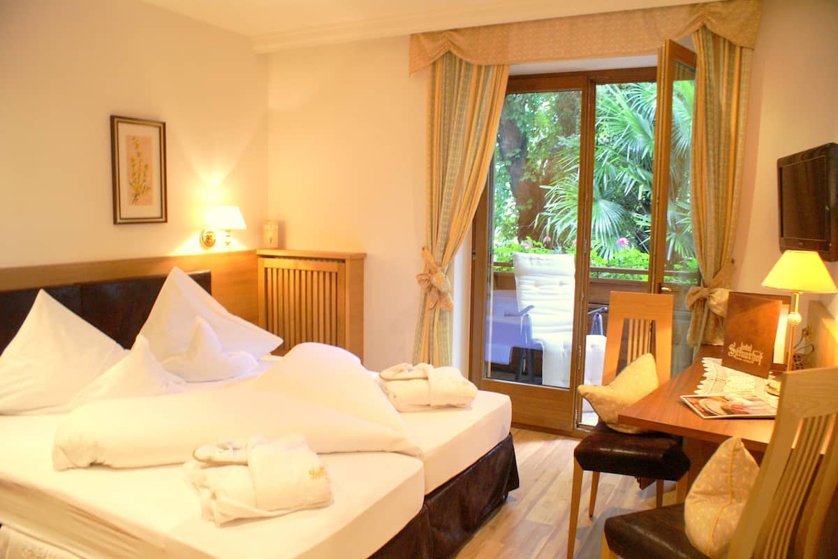 A hotel room with a bed, a desk, a chair, and a view of the outdoors.