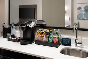 A hotel room with a coffee maker, a beverage dispenser, a snack bar, and a sink. - Embassy Suites by Hilton San Marcos Hotel Conference Center (San Marcos)