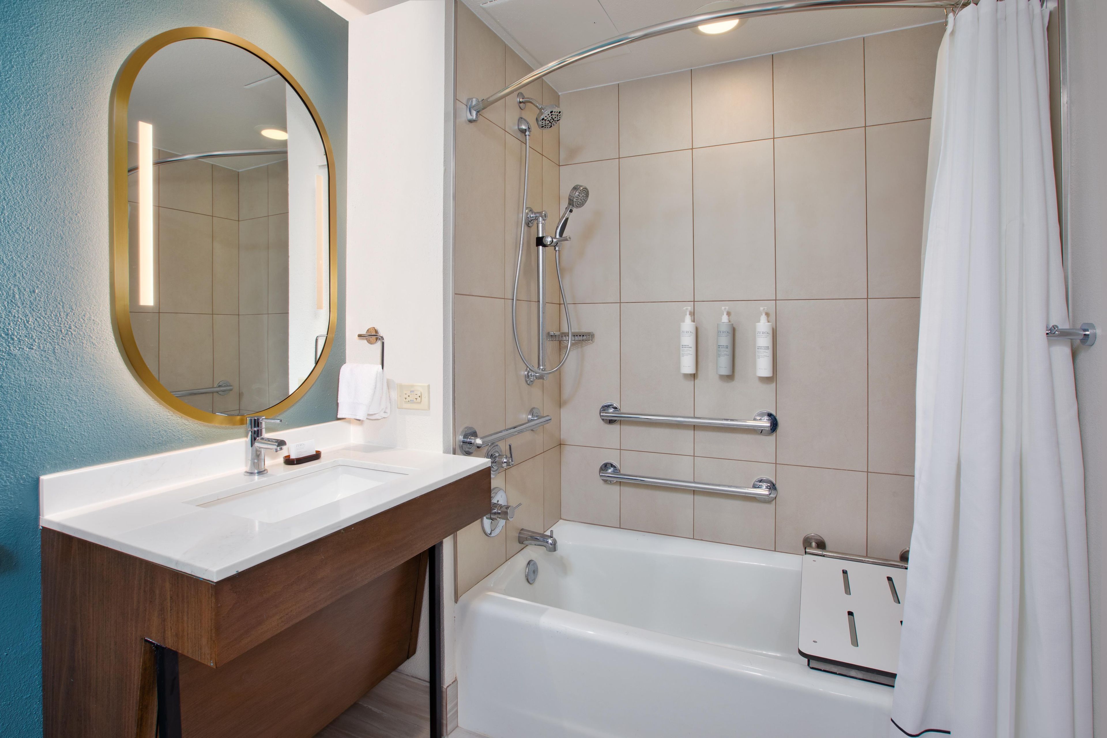 A modern bathroom with a white sink, a large mirror, a shower with a handheld showerhead, and a bathtub.