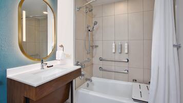 Un baño moderno con un lavamanos blanco, un espejo grande, una ducha con cabezal de ducha manual y una bañera.