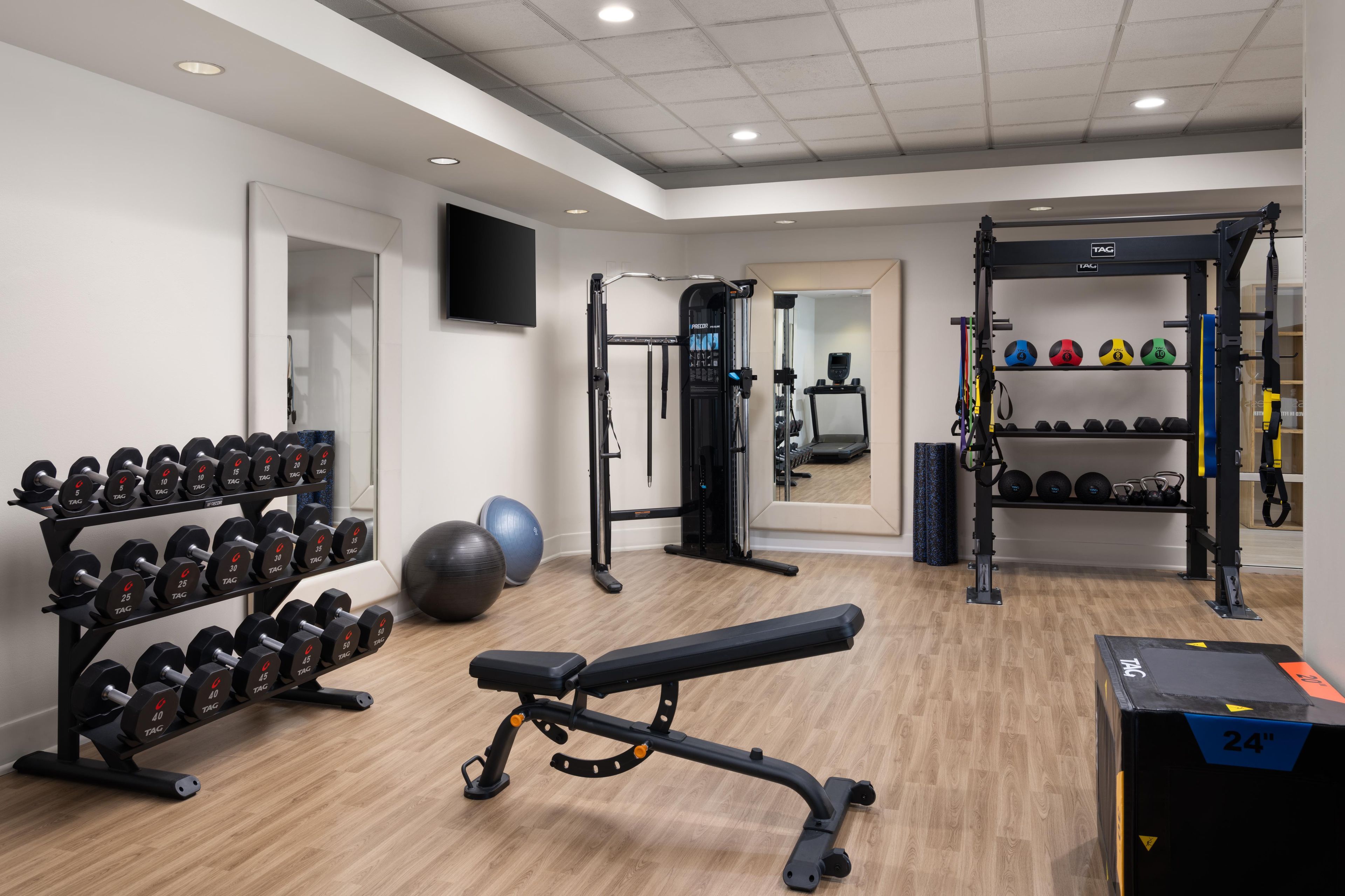 A gym with weightlifting equipment, exercise balls, and a bench.