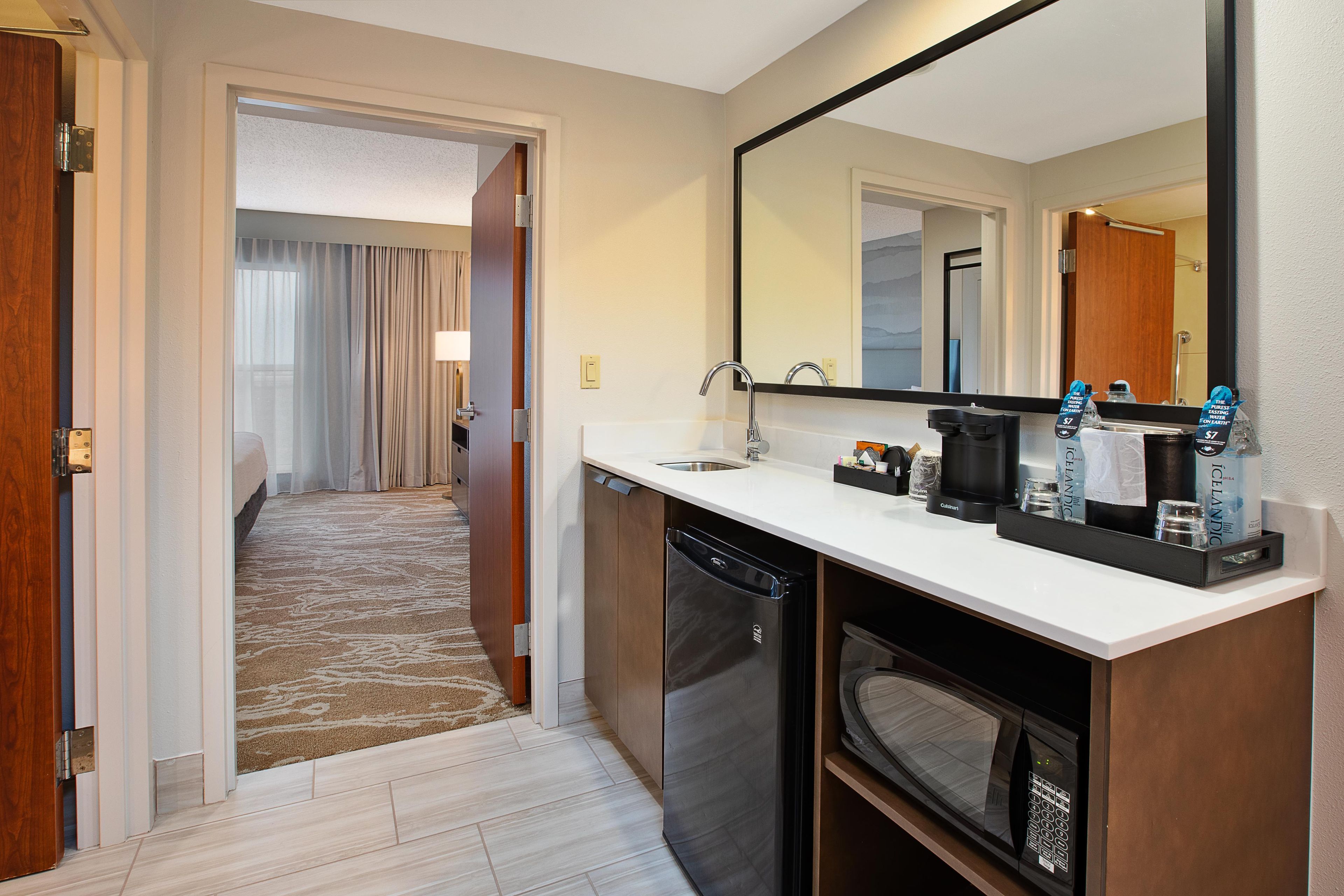 Un baño de hotel con lavamanos, espejo y cafetera.