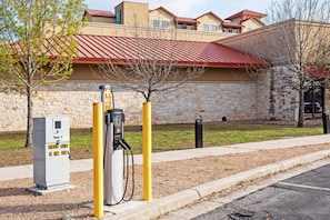 A public charging station with a stone building in the background. - Embassy Suites by Hilton San Marcos Hotel Conference Center (San Marcos)