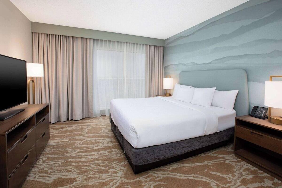 Een hotelkamer met een groot bed, een flatscreen televisie, een bureau en een lamp.