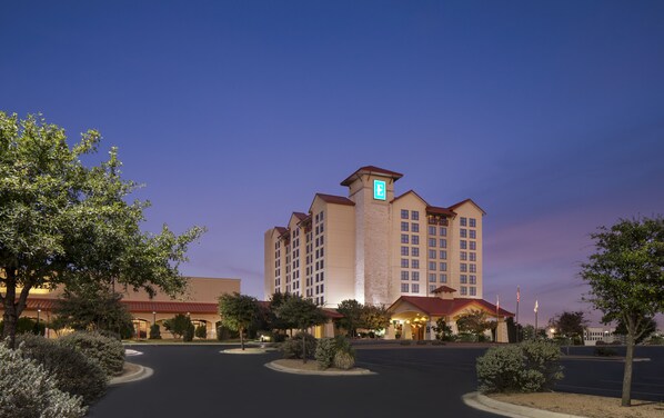 A large hotel with multiple floors, a prominent 'E' on the building, and a well-lit entrance. - Embassy Suites by Hilton San Marcos Hotel Conference Center (San Marcos)