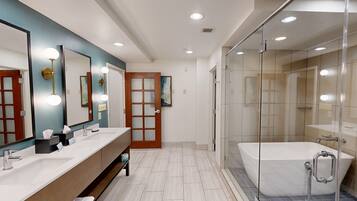 A modern bathroom with a large mirror, two sinks, a shower, and a glass-enclosed shower area.
