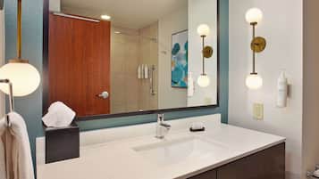 A bathroom with a white sink, a mirror, a towel rack, and a shower area.
