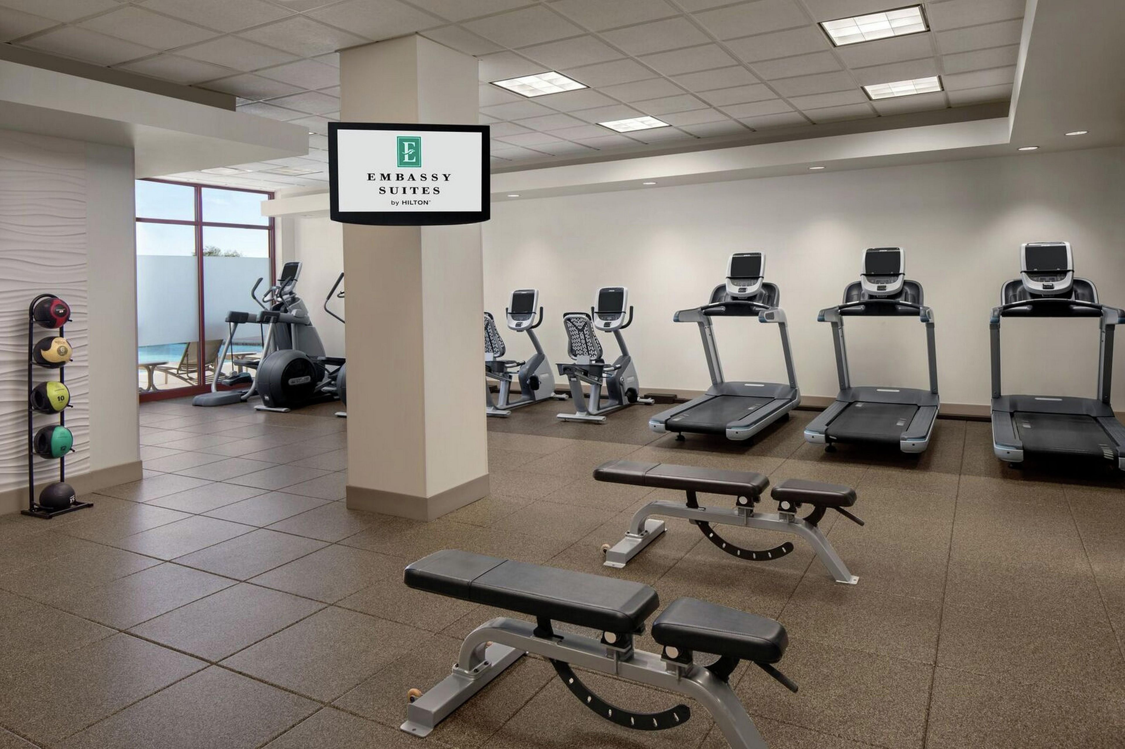 A fitness center with treadmills, elliptical machines, and a bench.