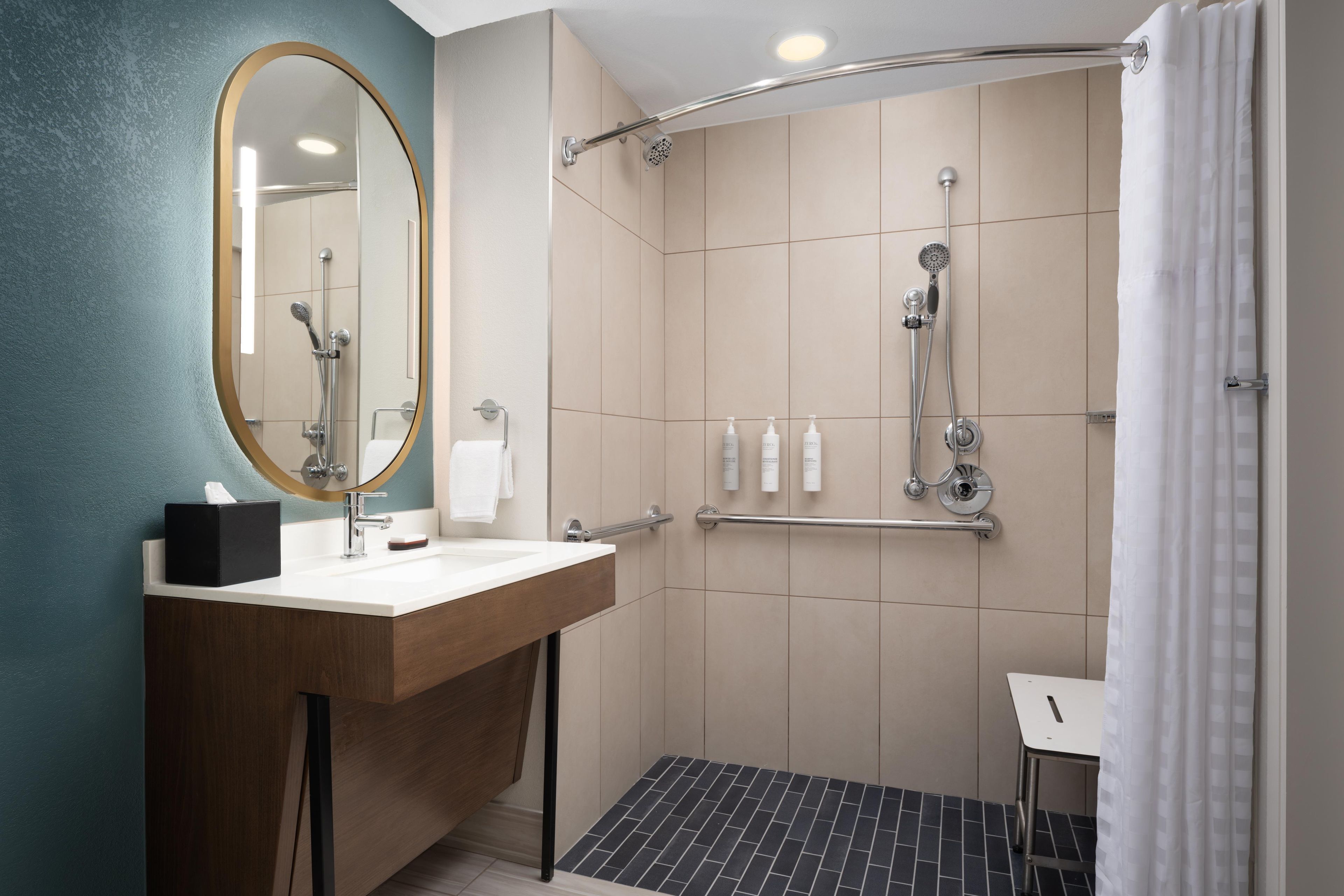 A modern bathroom with a shower, a sink with a mirror, and toiletries.