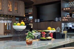 A bar area with a marble countertop, a bowl of fruits, a martini glass, and a drink with a lemon twist. - Embassy Suites by Hilton San Marcos Hotel Conference Center (San Marcos)