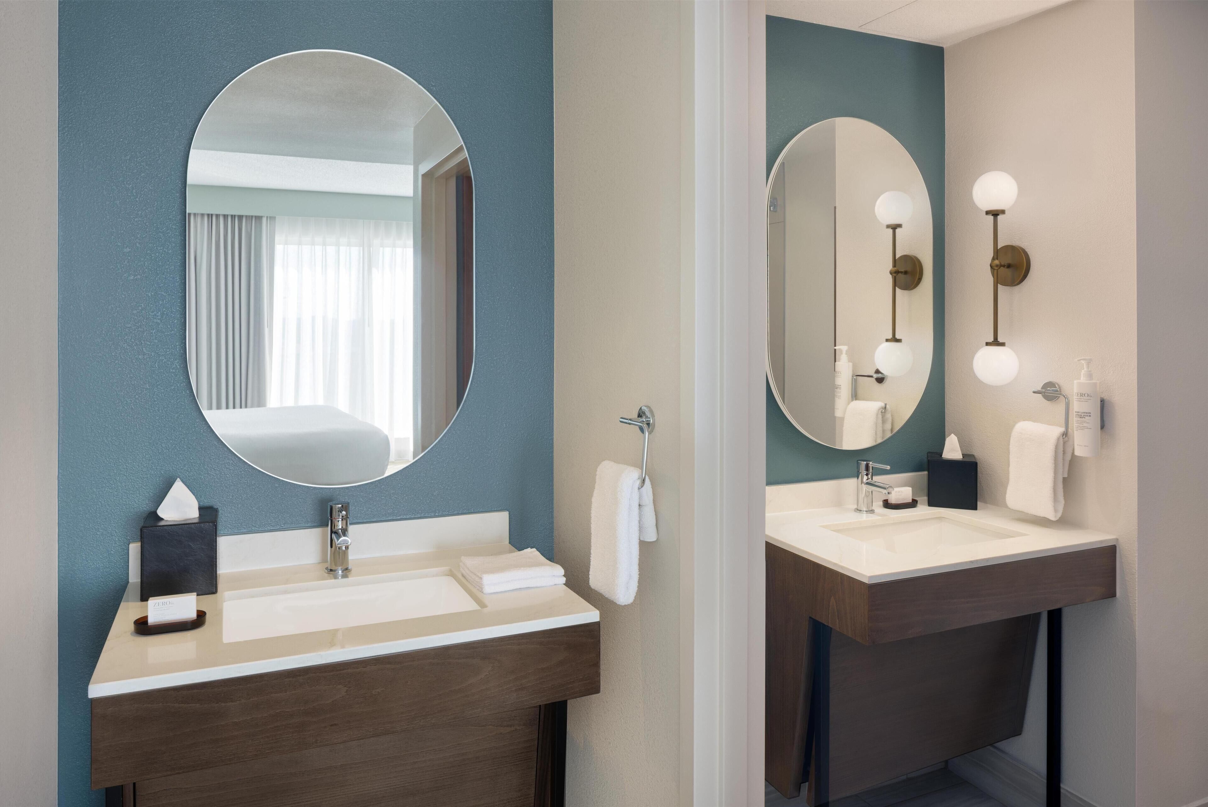 A modern bathroom with two sinks, a large mirror, and a towel rack.