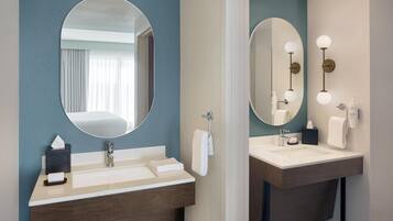 A modern bathroom with two sinks, a large mirror, and a towel rack.