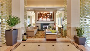 A spacious living area with a fireplace, sofas, and a coffee table. - Hilton Garden Inn Sacramento Elk Grove (Elk Grove)