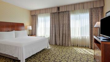 A hotel room with a large bed, two bedside tables, a flat-screen TV, and a patterned carpet.