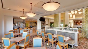 A restaurant with booths and tables, a TV mounted on the wall, and patterned flooring. - Hilton Garden Inn Sacramento Elk Grove (Elk Grove)