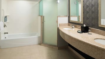 A bathroom with a bathtub, a glass shower enclosure, and a vanity with two sinks and a mirror.