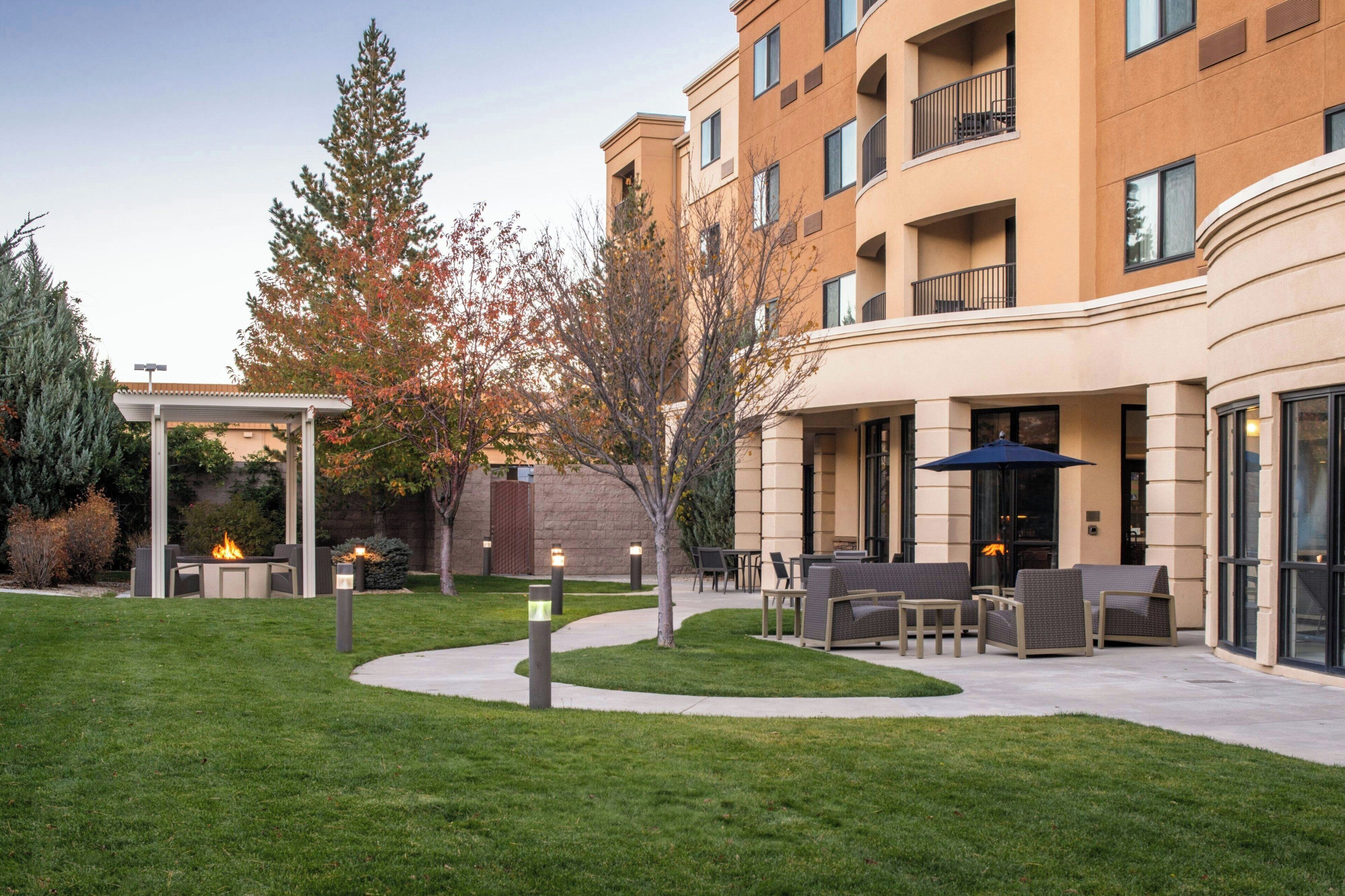 A courtyard with outdoor seating, a pergola, and a building with multiple balconies.