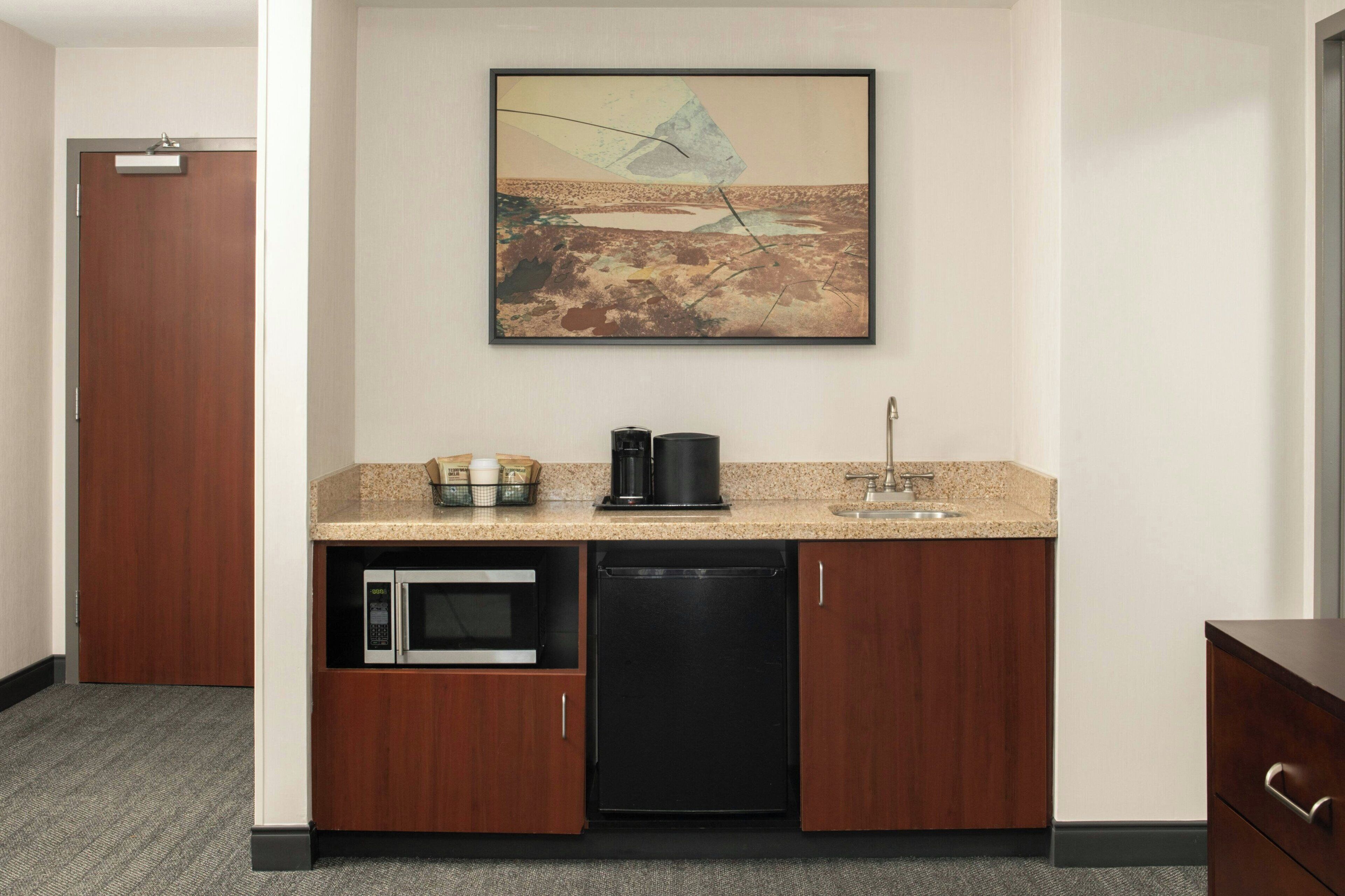 A compact kitchen with a microwave, coffee maker, and a sink.