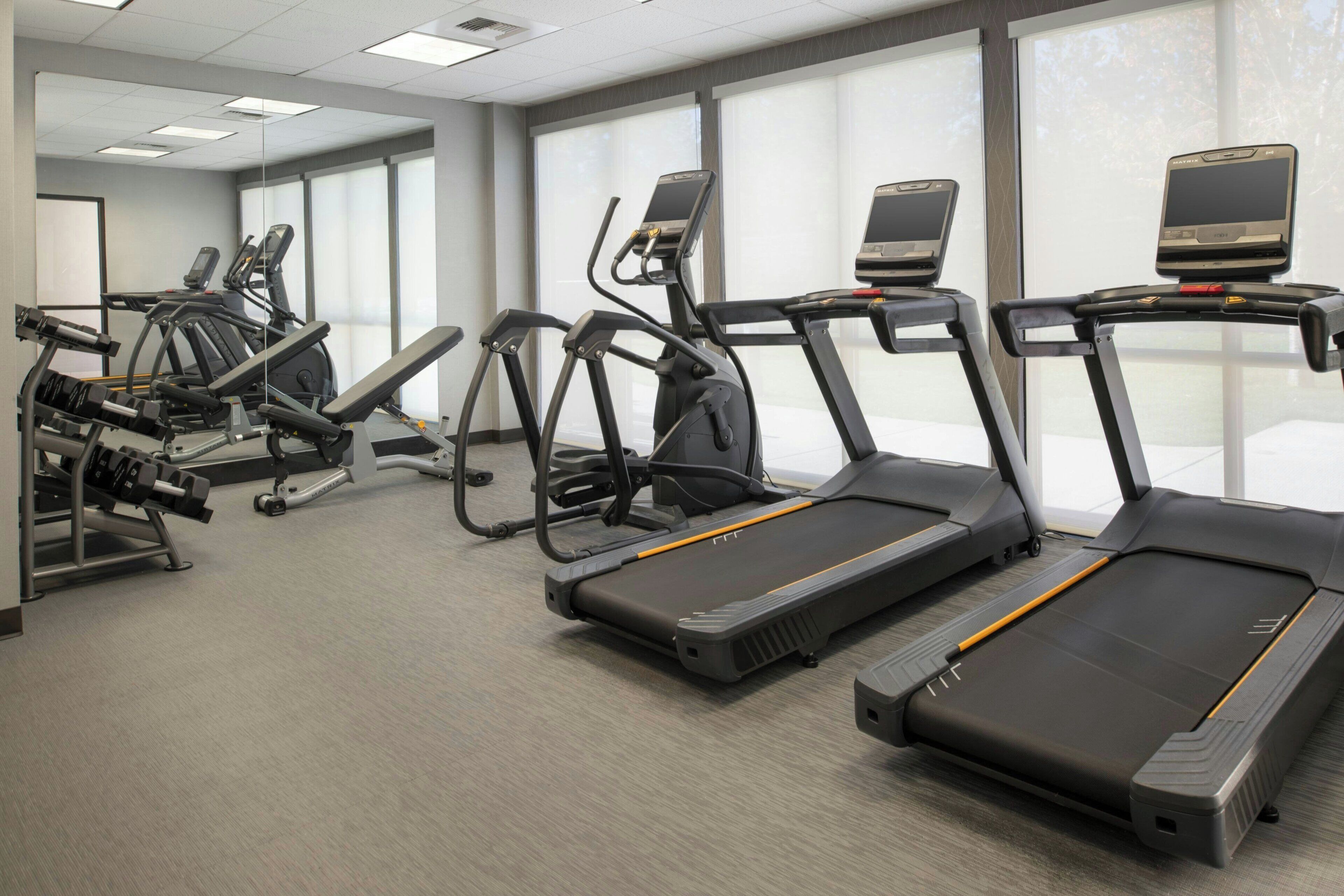 A gym with treadmills, elliptical machines, and weight equipment.