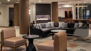 A modern lobby with a sectional sofa, armchairs, a round coffee table, and a fireplace. - Courtyard by Marriott Carson City (Carson City)