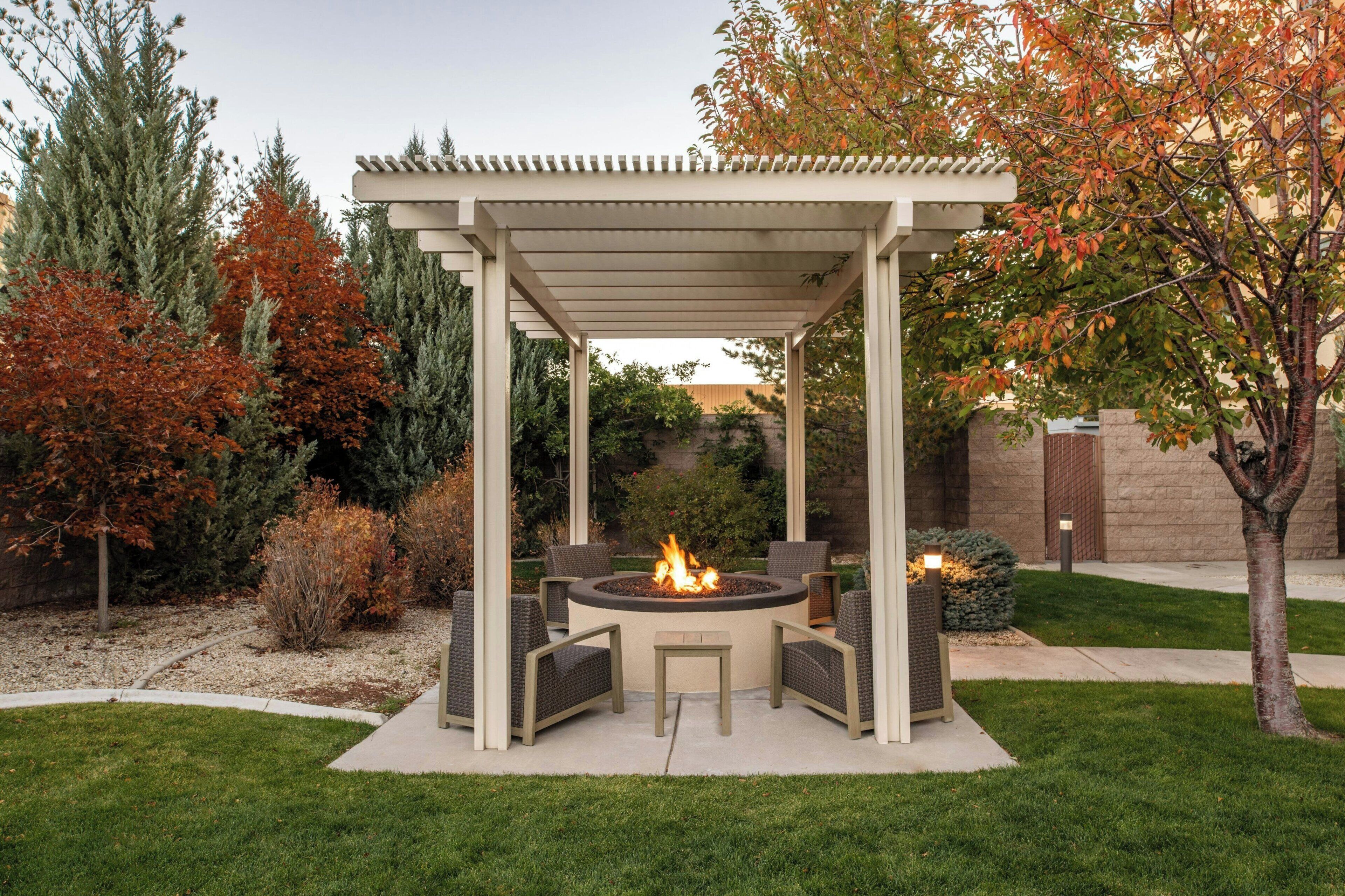 A covered outdoor patio with a fire pit, seating, and a pergola structure.