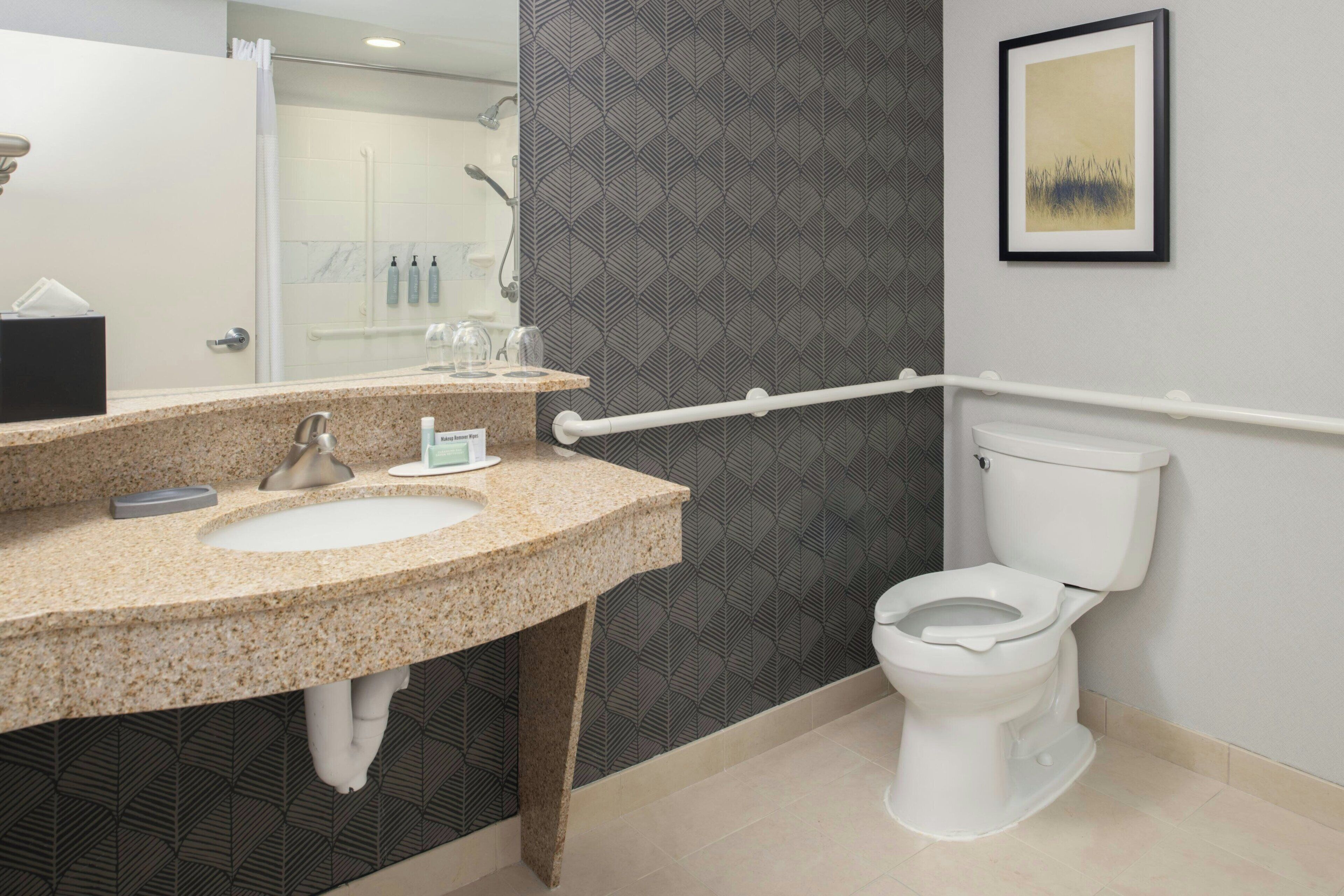 Un baño moderno con lavamanos de granito, inodoro blanco y zona de ducha.