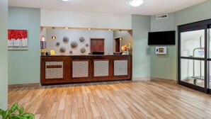 A reception area with a wooden counter, a flat-screen TV, and a large window. - Best Western Plus Hopewell Fort Lee (Hopewell)