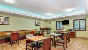 A restaurant with wooden flooring, multiple tables and chairs, a television, and framed artwork on the walls. - Best Western Plus Hopewell Fort Lee (Hopewell)