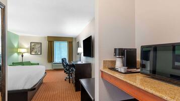 Habitación de hotel con cama, escritorio, silla, televisor, cafetera y microondas.