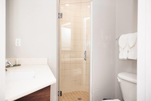 A bathroom with a shower, sink, and toilet.