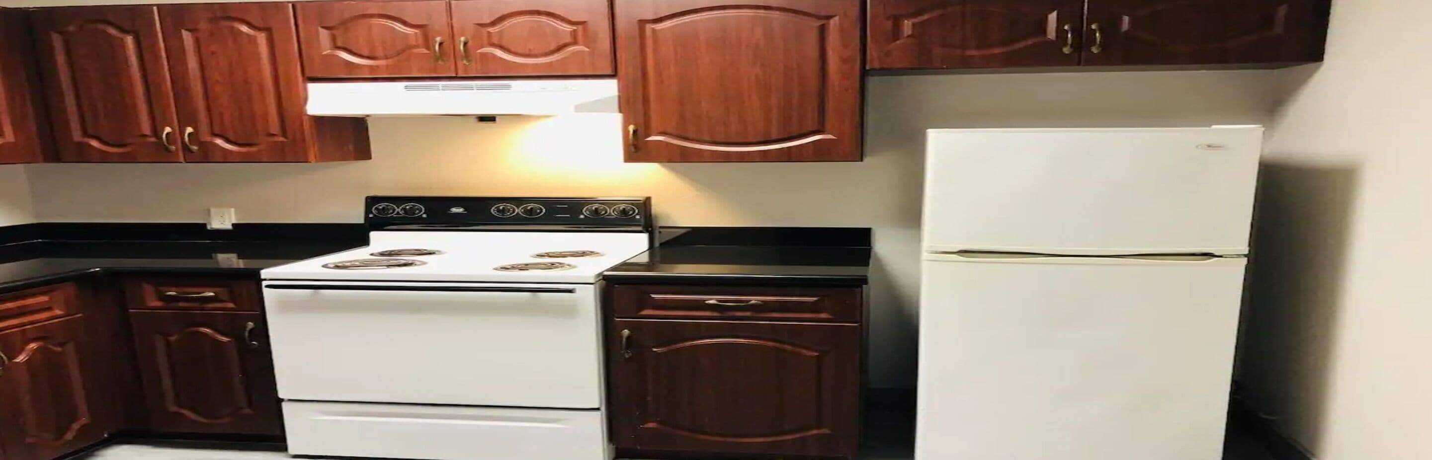 Une cuisine avec des meubles en bois, un fourneau blanc et un réfrigérateur blanc.