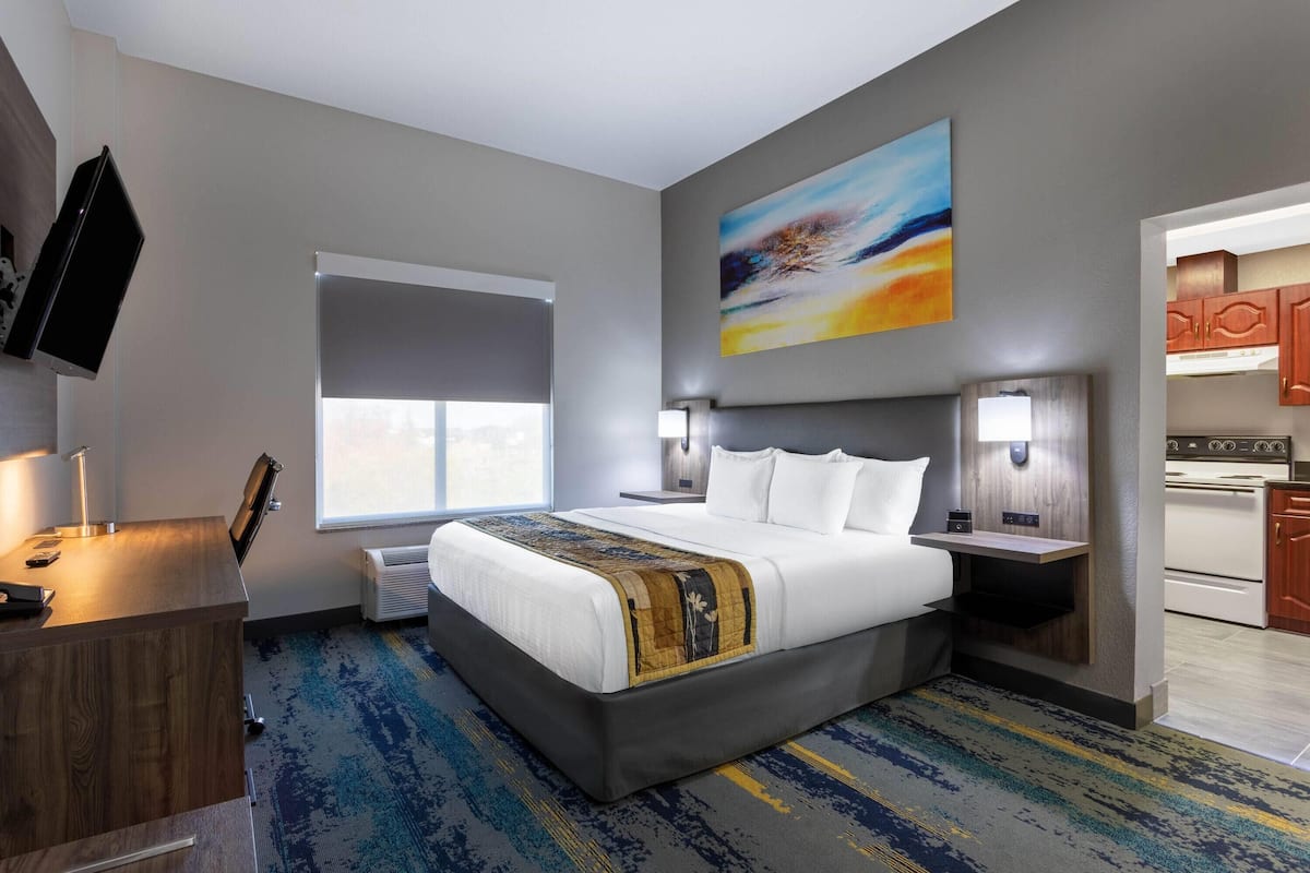 Ein Hotelzimmer mit Bett, Nachttischen, Fernseher, Fenster und einer Küchenzeile.