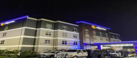 A multi-story hotel with 'LA QUINTA' signage, a gas station, and several vehicles parked in front.
