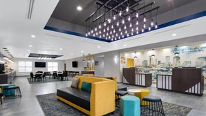 Un hall d’hôtel moderne avec un canapé, un espace salon et un comptoir d’accueil.