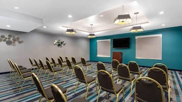 A conference room with rows of chairs, a flat-screen TV, and a projector screen.