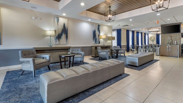 A spacious lobby with a long sofa, armchairs, and a dining area.