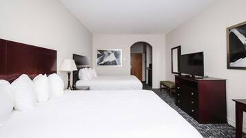 Habitación de hotel con dos camas, un televisor, un aparador y un cuadro en la pared.