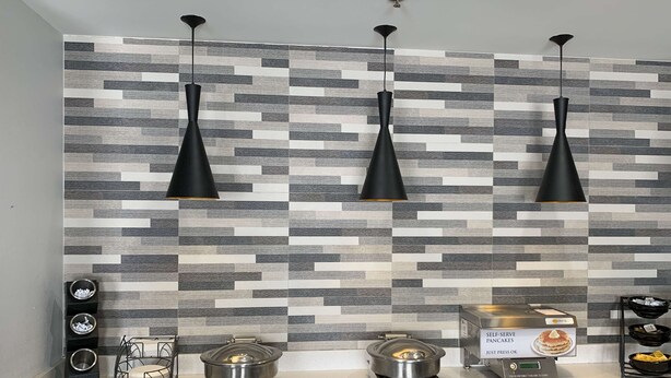 Cozinha moderna com mosaico no painel de fundo, luminárias pendentes pretas e espaço para preparo de panquecas.