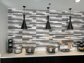 Una cocina moderna con un salpicadero de diseño, luces colgantes negras y una estación de panqueques tipo autoservicio.