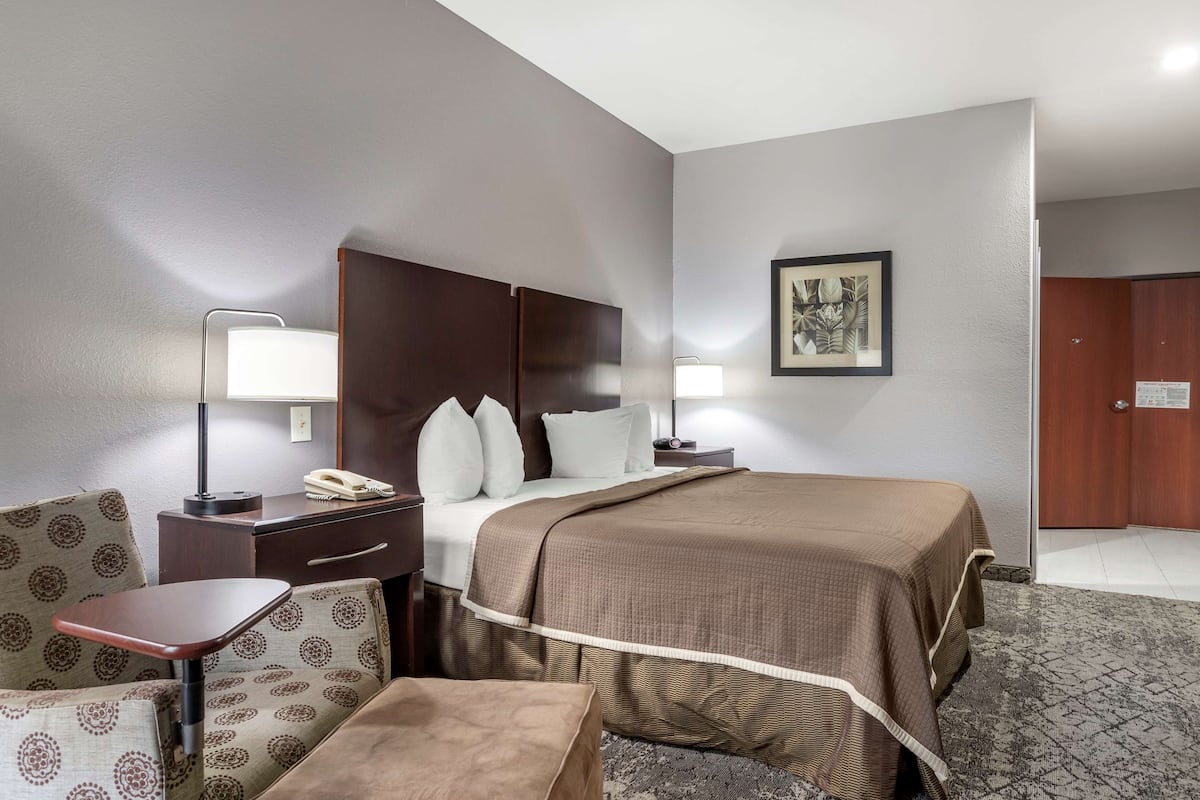 A hotel room with a bed, bedside tables, a chair, and a desk.