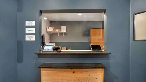 A reception desk with a computer, a phone, and a small display. There are signs indicating check-in and check-out times, an office, and a no-smoking policy. - Extended Stay America Select Suites - Tallahassee - East (Tallahassee)
