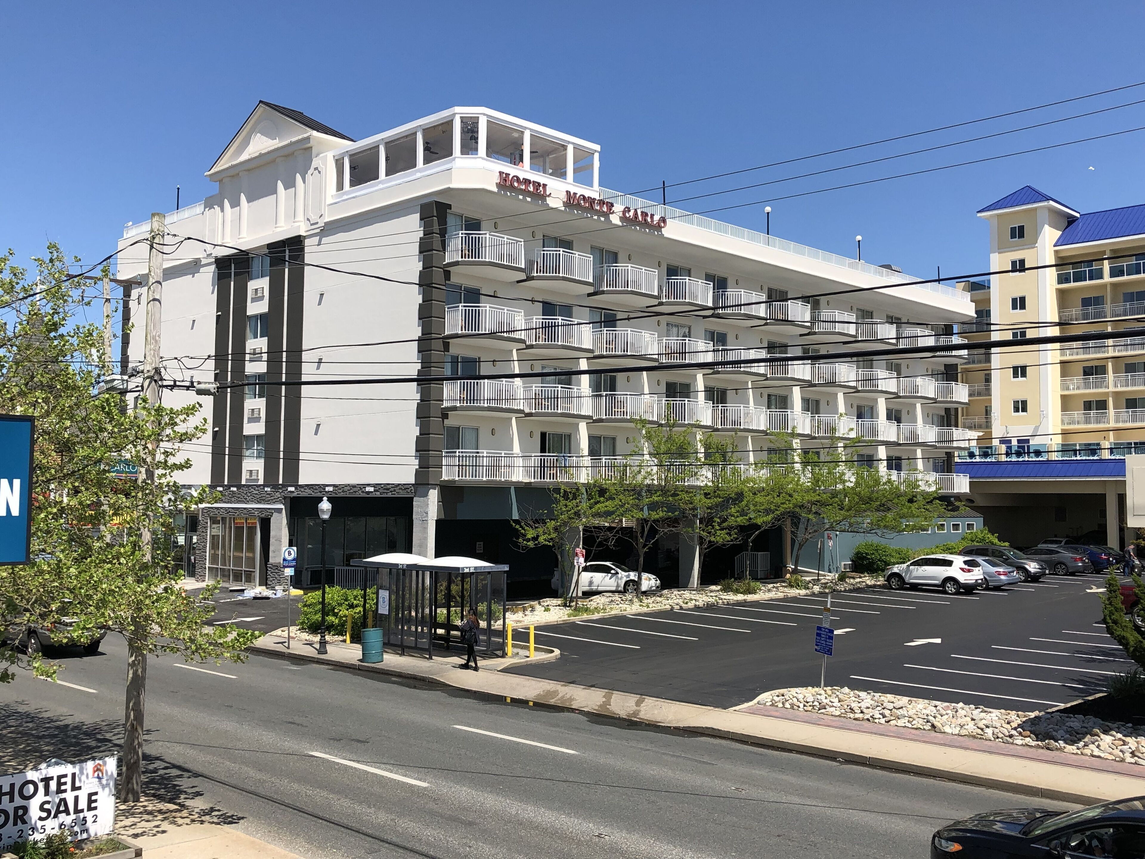 Un hotel de varios pisos con balcones, una entrada cubierta y un estacionamiento.