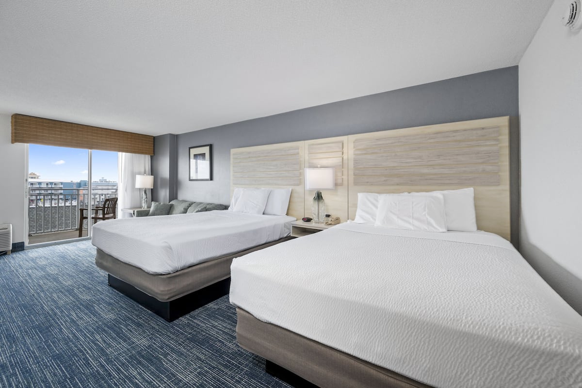 A hotel room with two beds, a large window with a view, and a balcony.