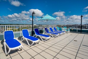 Terraza en la azotea con sillones azules y un parasol a rayas.
