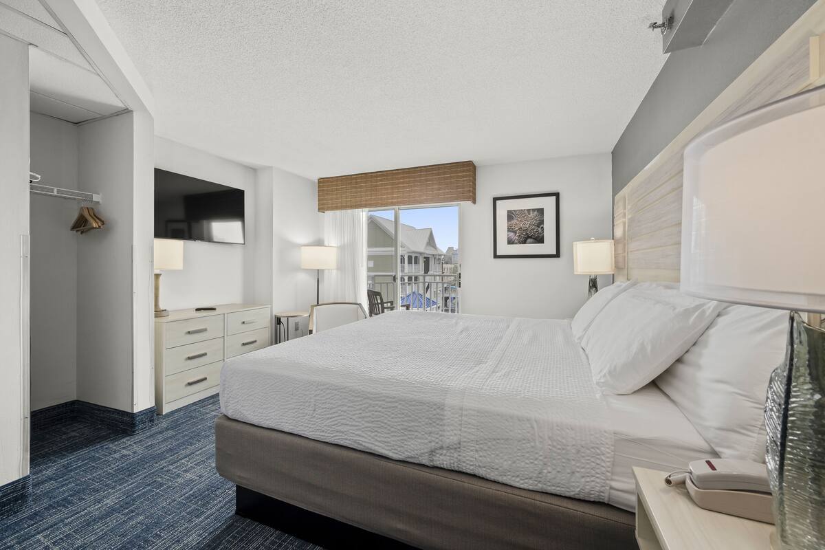 A hotel room with a large bed, bedside tables, a desk, and a chair.