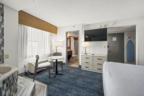 Habitación de hotel con cama, escritorio, silla, baño y televisión.