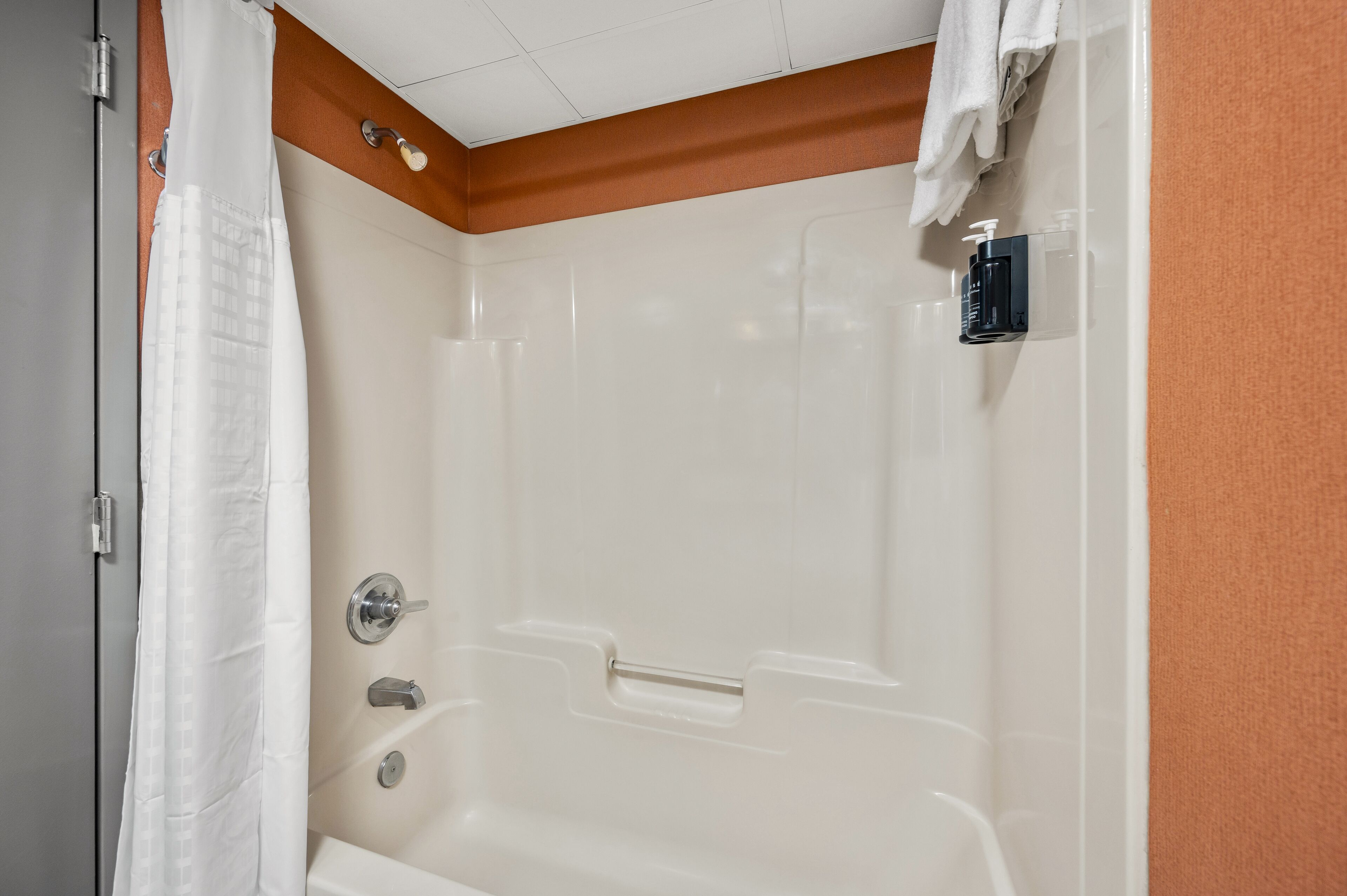 Un baño con bañera, cortina de ducha y toallero.