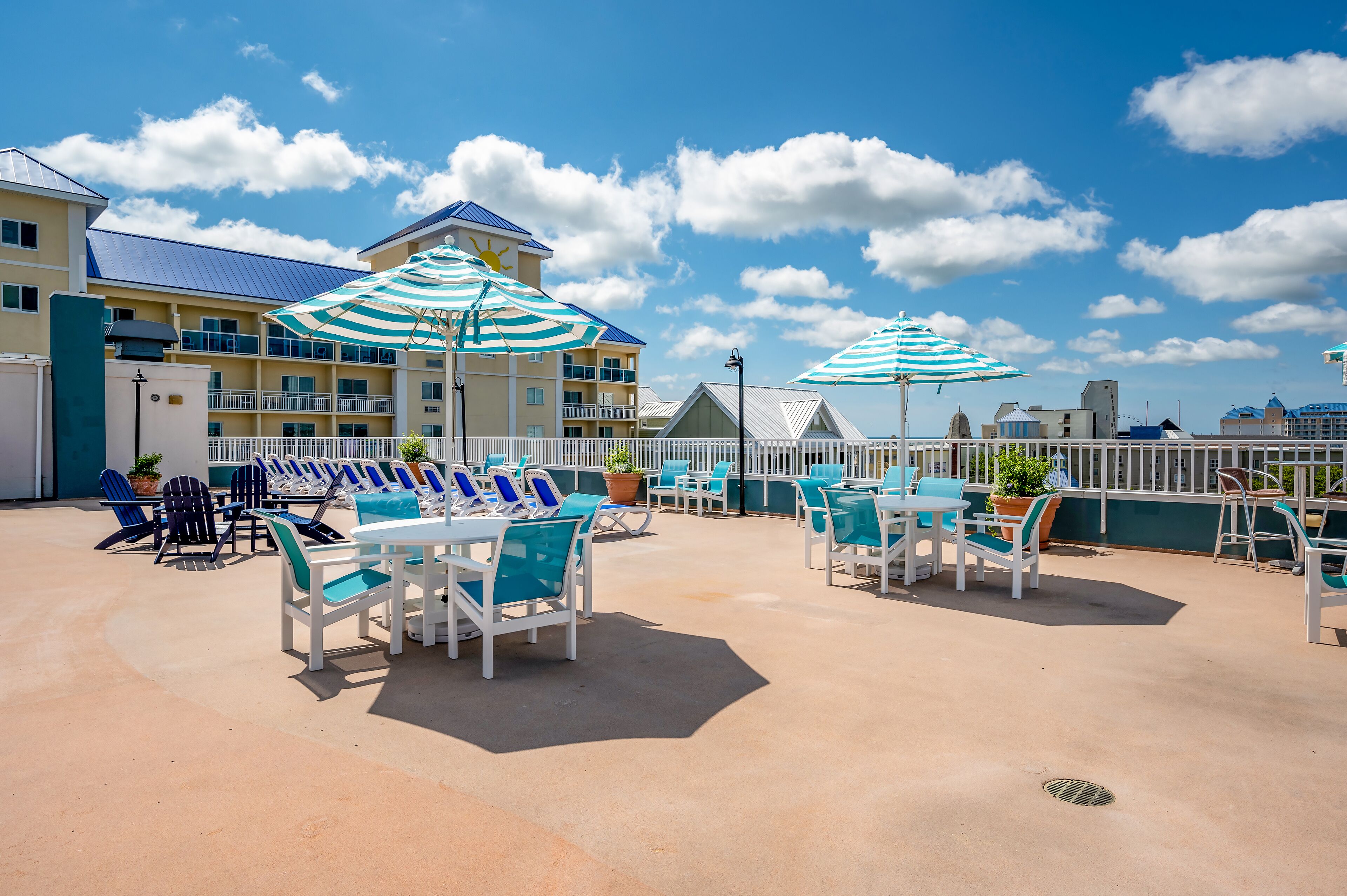A rooftop patio with outdoor seating, umbrellas, and a view of the hotel buildings.