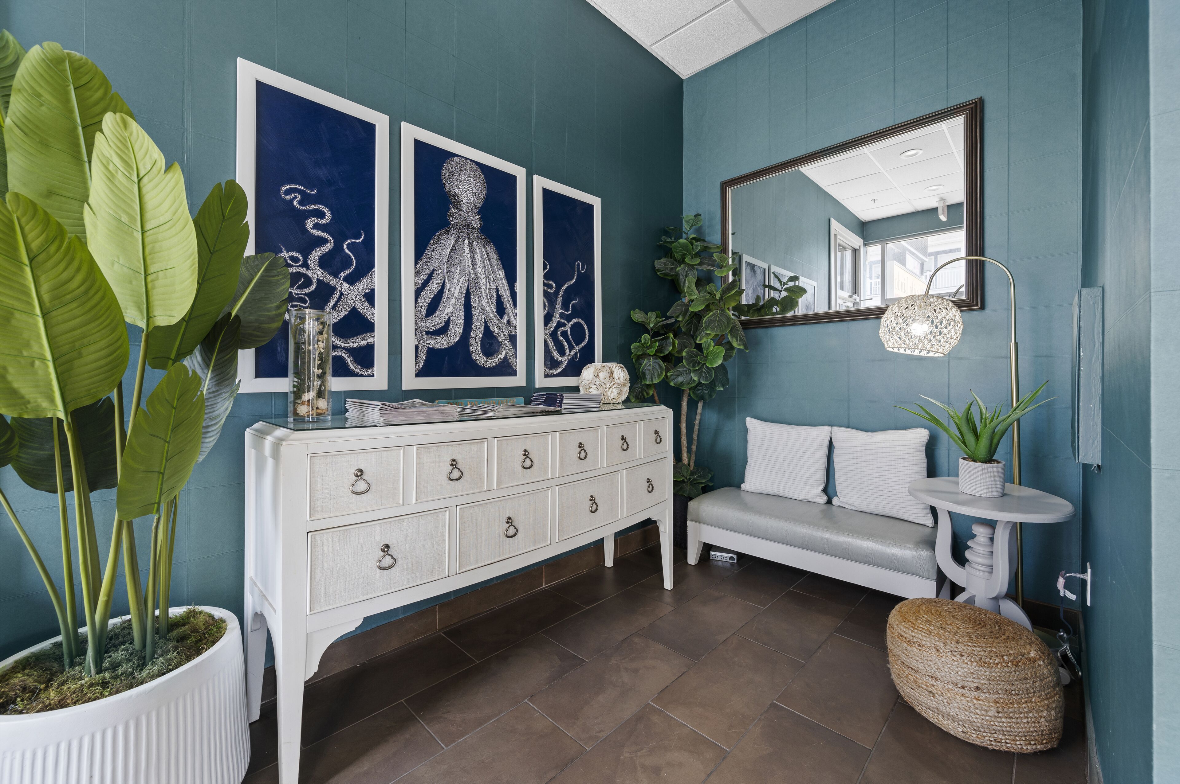 Una habitación con un aparador blanco, un sofá gris y una planta grande en maceta.